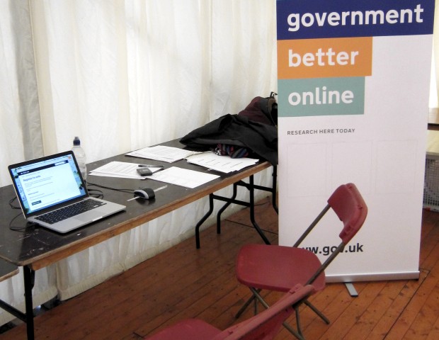 Example of a popup research set up, with a GDS poster, folding chairs and table and a laptop. 