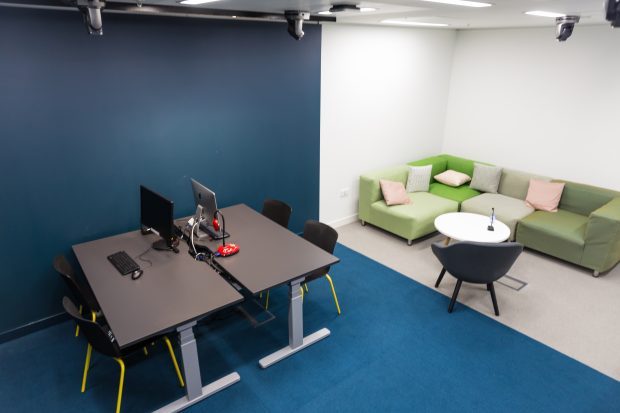 A picture of an empty user research room with sofa, chairs, desks and computers