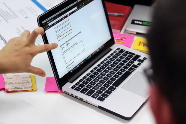 2 people looking at a digital service on a computer screen. Only their hands are visible