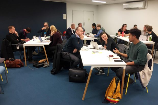 Some of the attendees at a cross government training event, sitting at tables talking